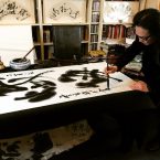 A photo of Zhao Yizhou performing a calligraphic work for the filming of Traces Of The Soul documentary